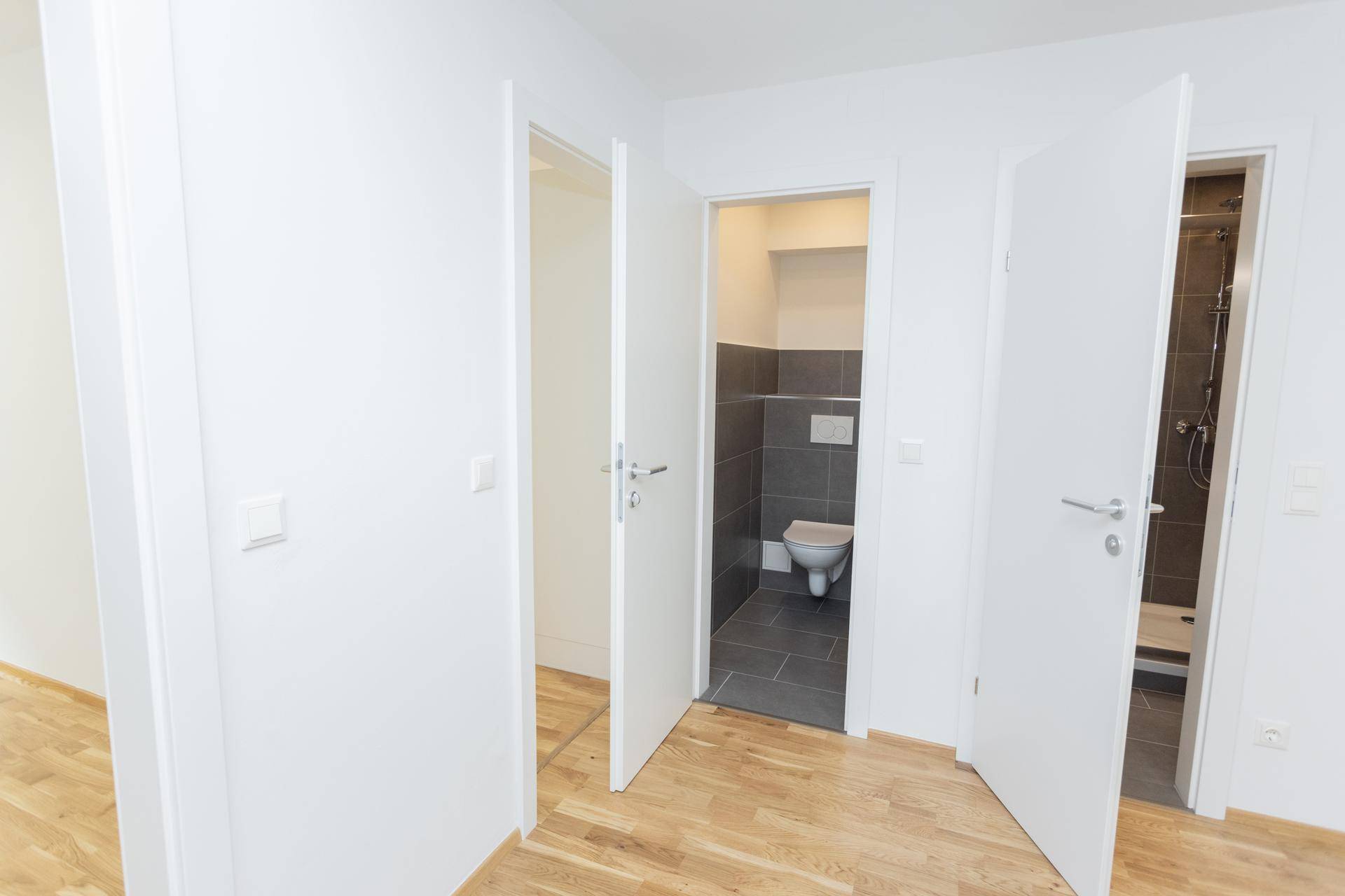 Blick auf offene Türen, die zu einem separaten WC und einem modernen Duschbad führen.