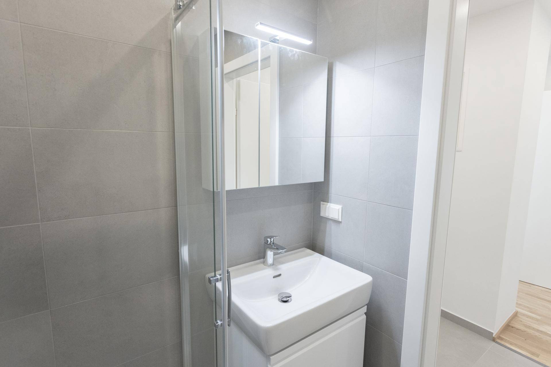 Modernes Badezimmer mit Waschtisch, Spiegelschrank und Duschkabine.