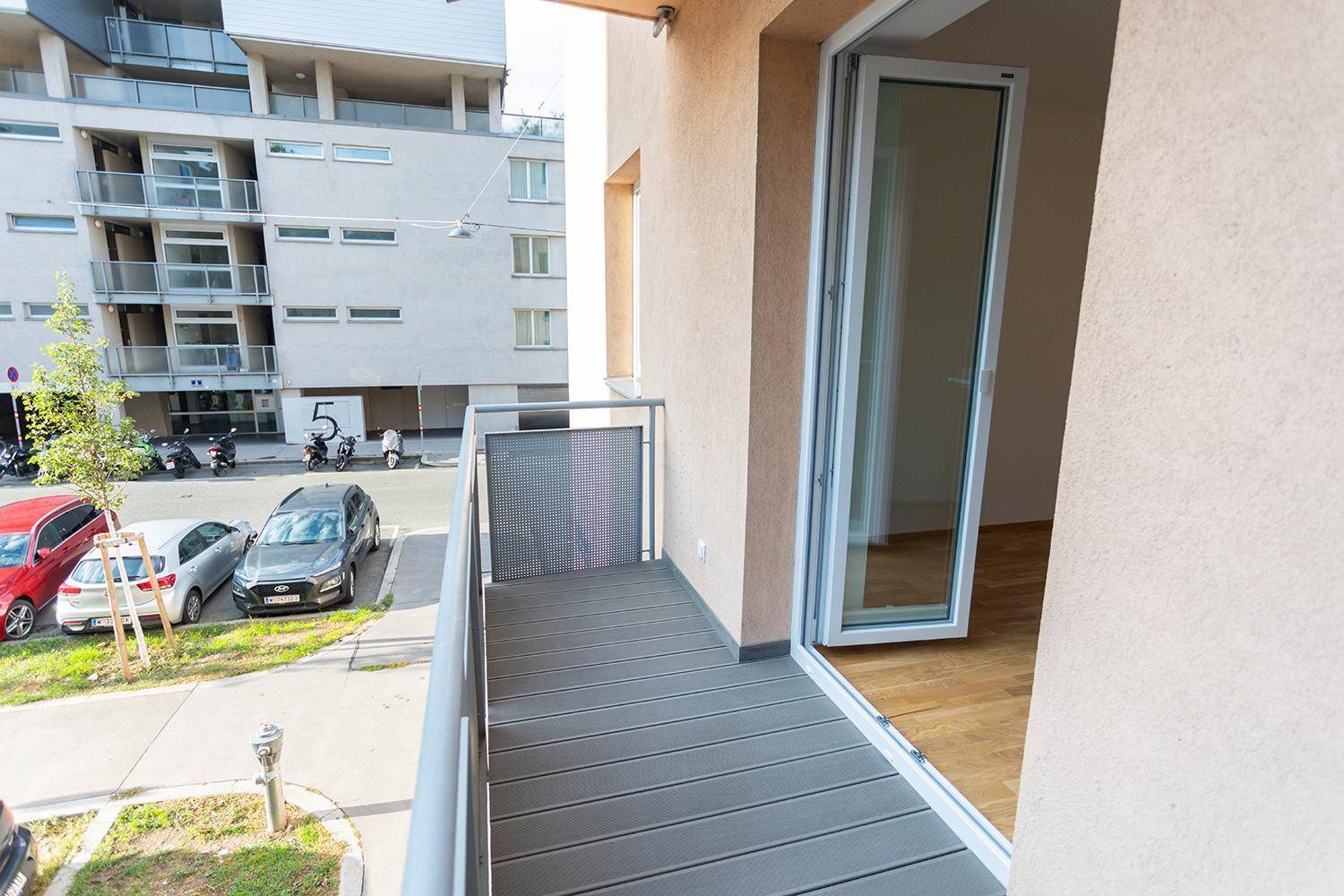 Balkon mit modernem Bodenbelag und Ausblick auf die städtische Umgebung.