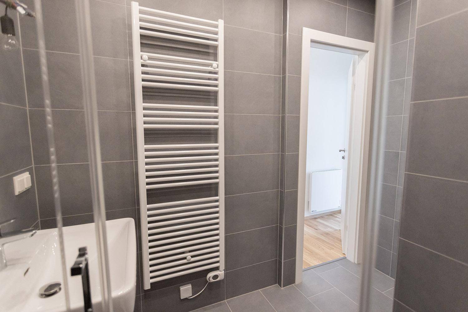 Beheizter Handtuchhalter in einem modern gefliesten Badezimmer, der für Komfort sorgt.