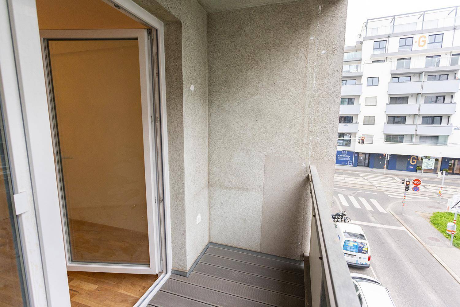 Balkon mit Blick auf die Straße und die umliegende Stadtbebauung, ausgestattet mit modernem Dielenboden.