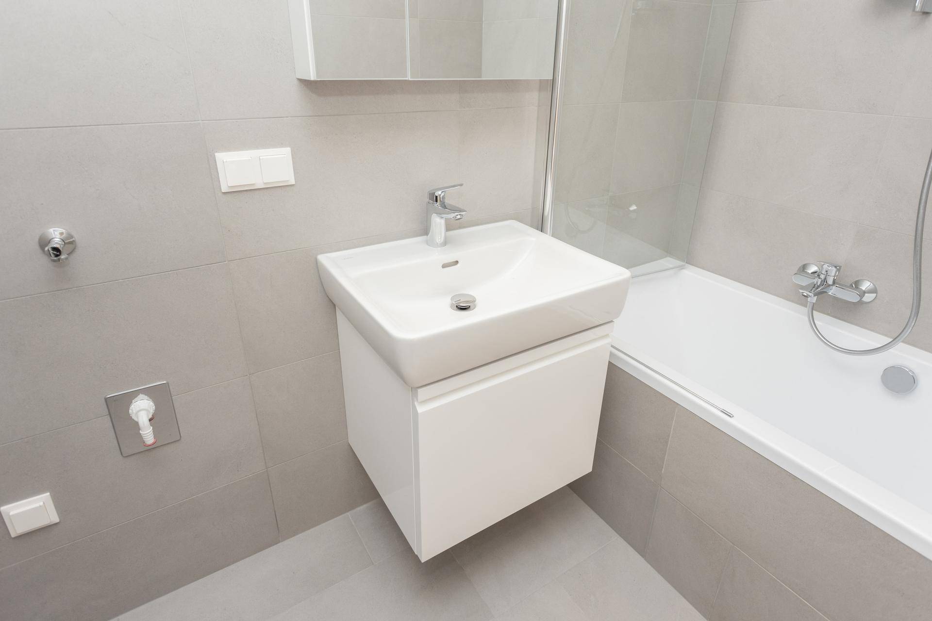 Detailansicht des Waschbeckens mit Unterschrank im modern gefliesten Badezimmer, in Grau und Weiß.