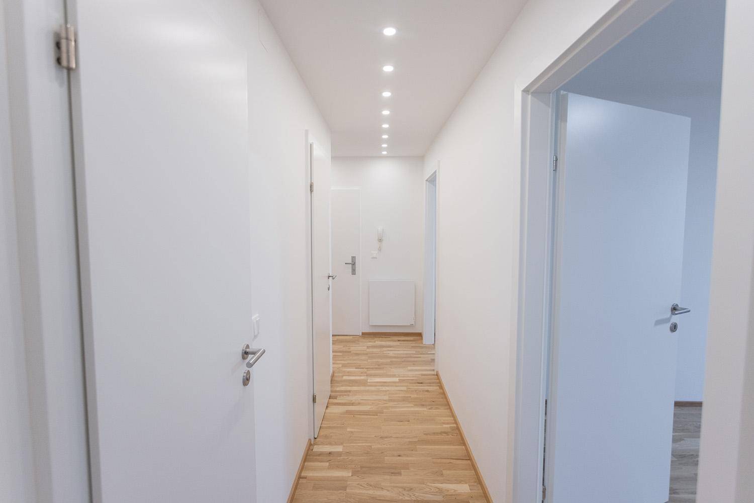 Geräumiger Flur mit Holzboden und mehreren Türen, der verschiedene Räume verbindet.