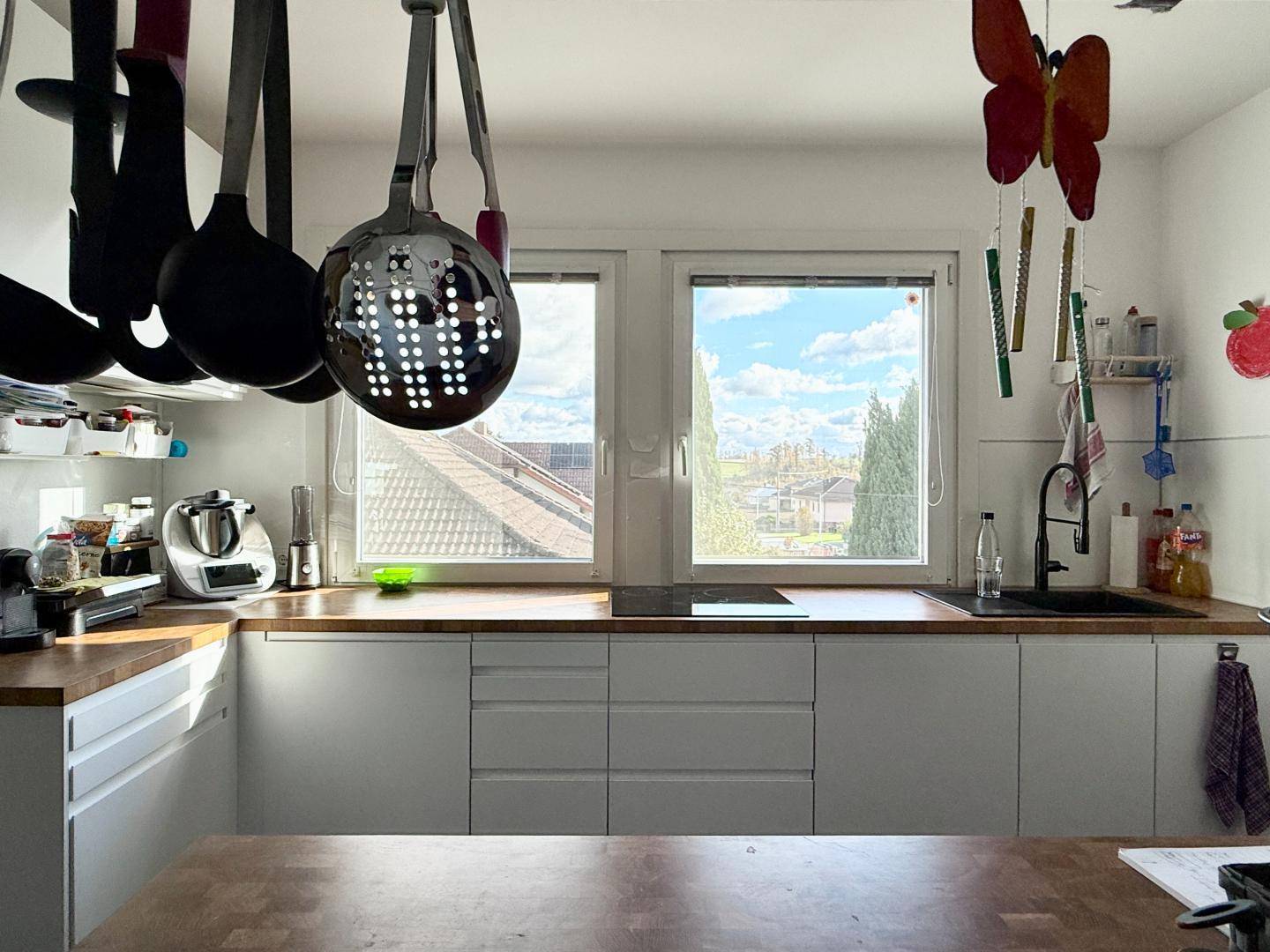 Funktionale Küche mit viel Tageslicht, Holz-Arbeitsplatte und Blick in die Umgebung.