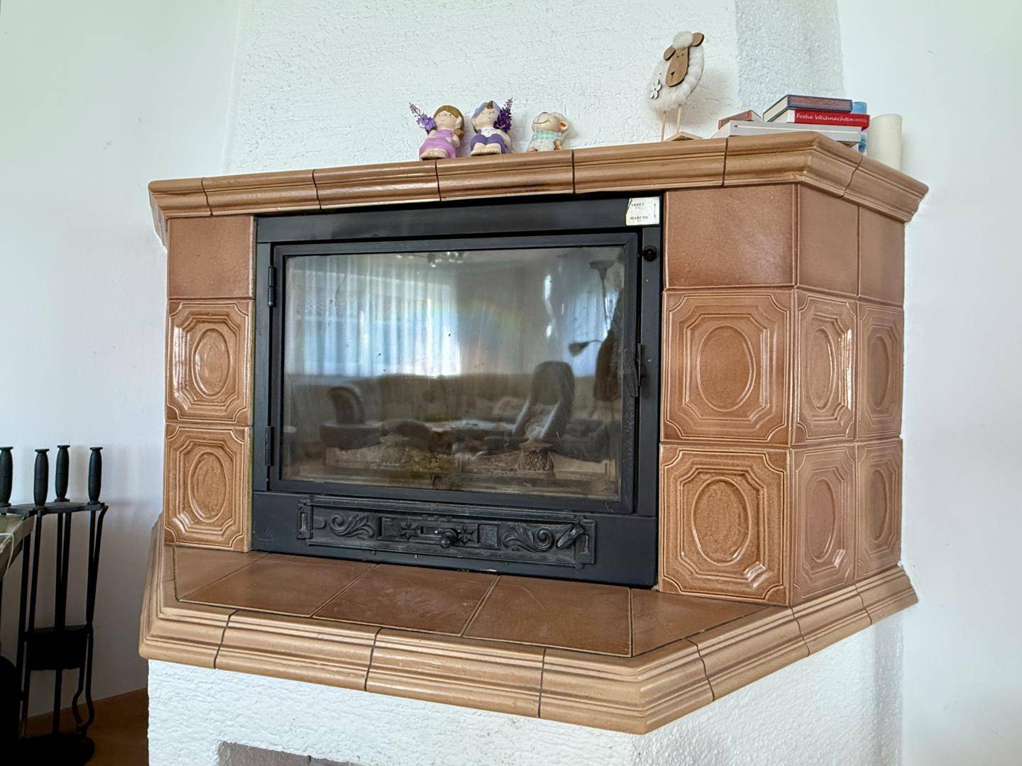 Gemütlicher Kaminofen mit Kacheln im Wohnbereich, ideal für kalte Tage.