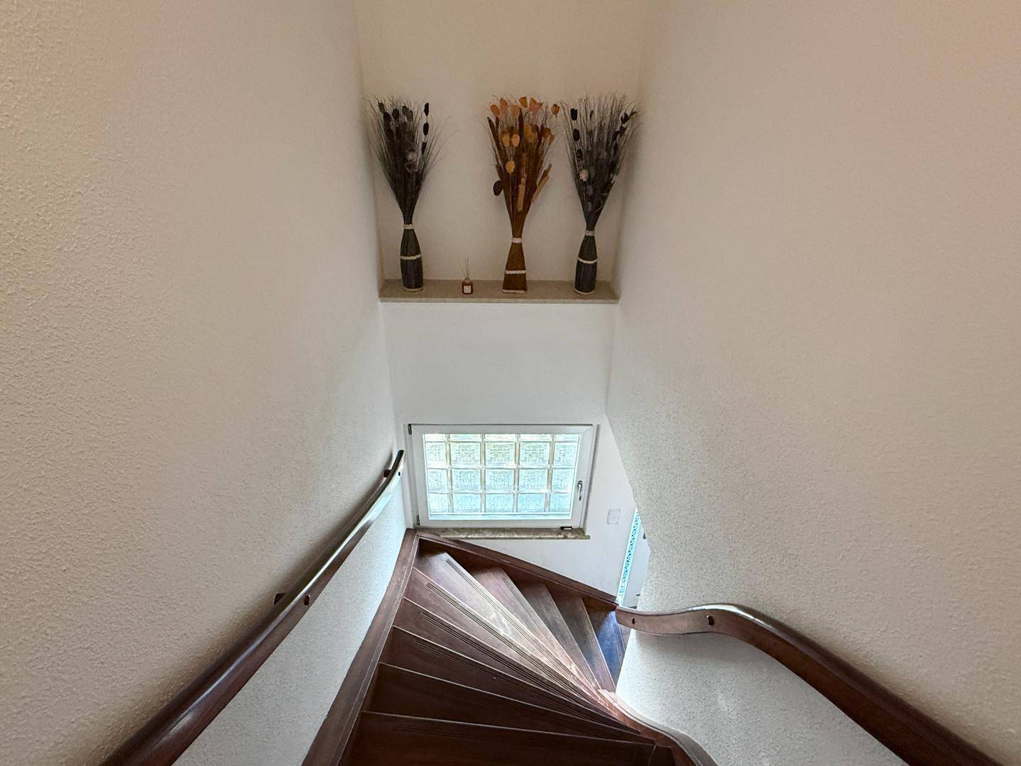 Holztreppe führt in das obere Stockwerk, beleuchtet durch ein Fenster.