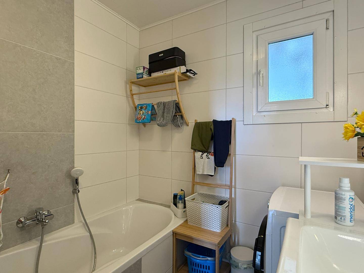 Badezimmer mit Badewanne, Waschmaschine und Fenster für natürliche Belüftung.