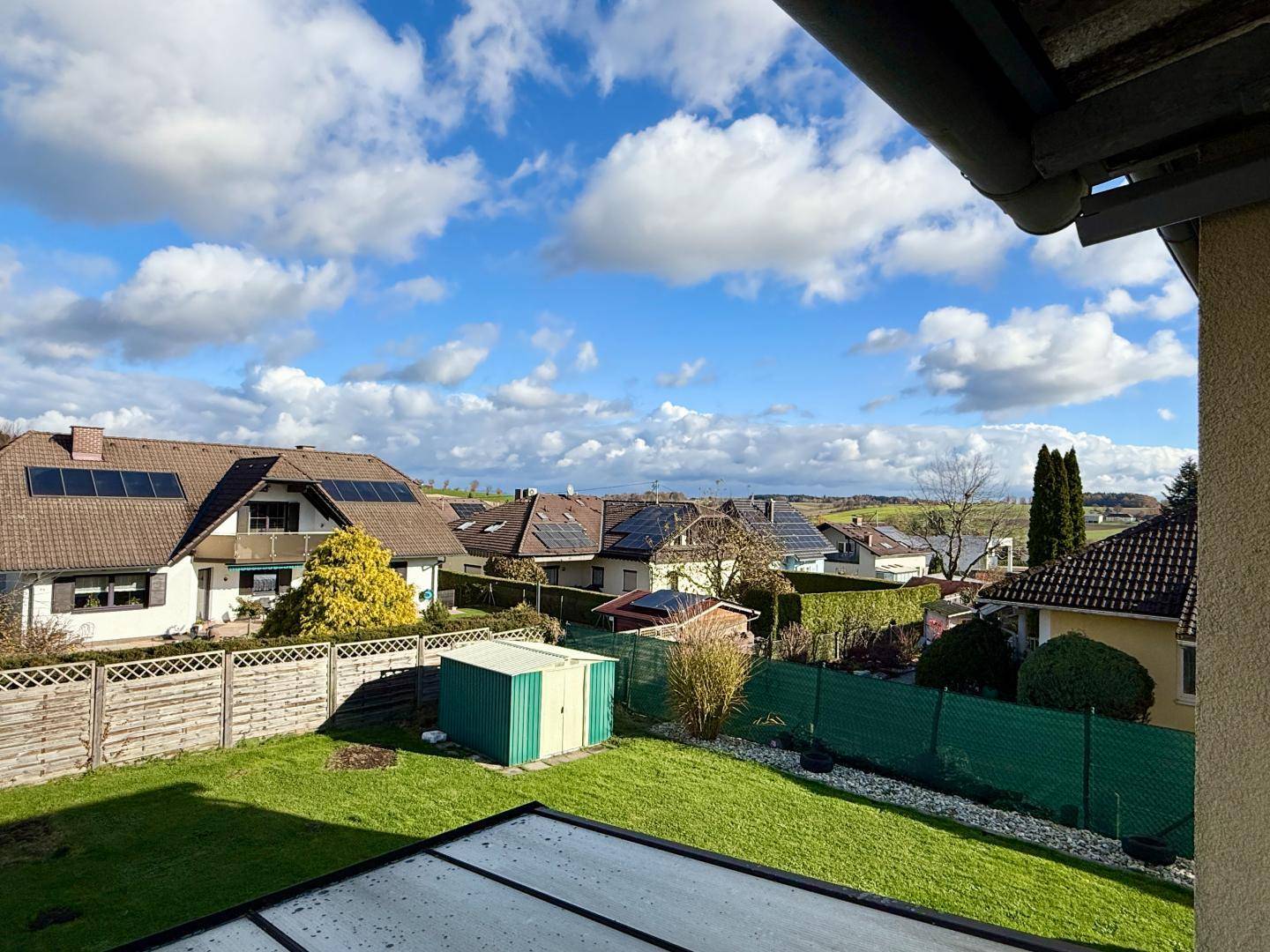 Panoramablick vom Balkon auf die grüne Landschaft und die benachbarten Häuser.