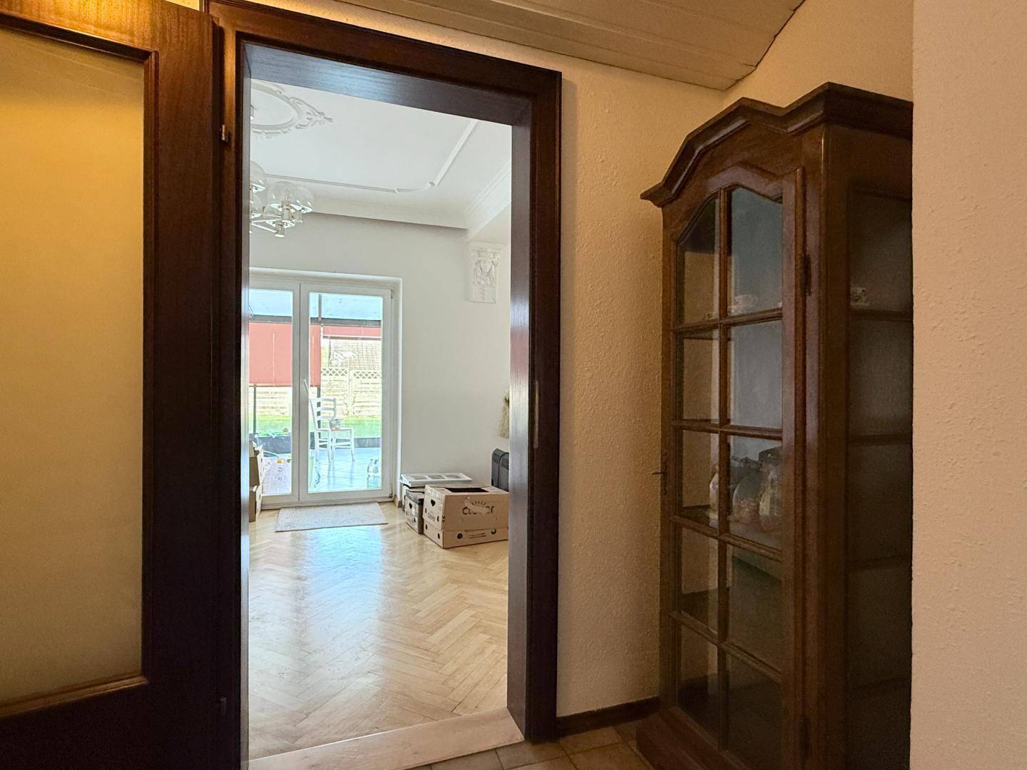 Flur mit Holztürrahmen und Blick in das helle Wohnzimmer mit Parkettboden.