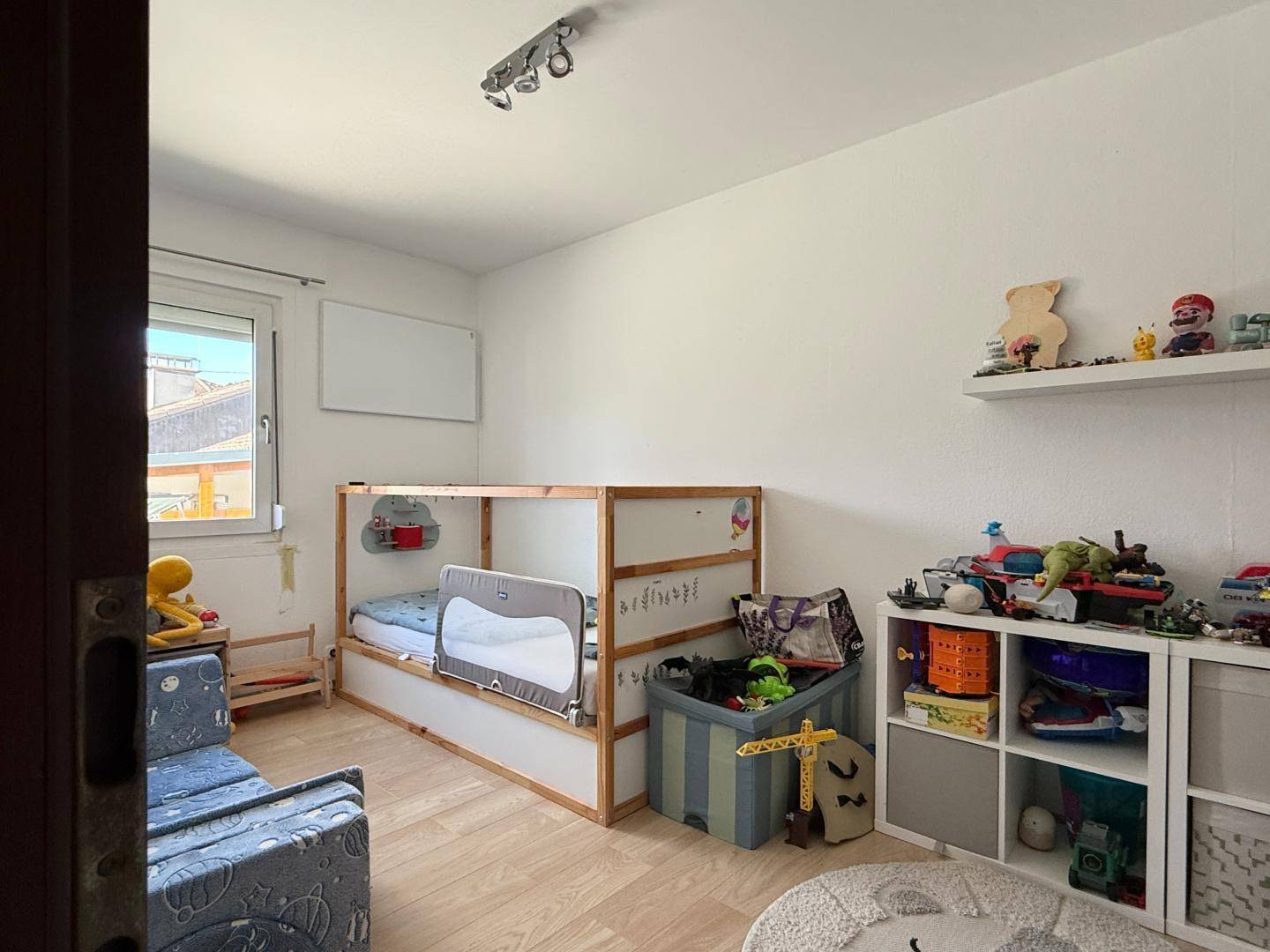 Kinderzimmer mit hellem Holzbett und viel Platz zum Spielen und Lernen.