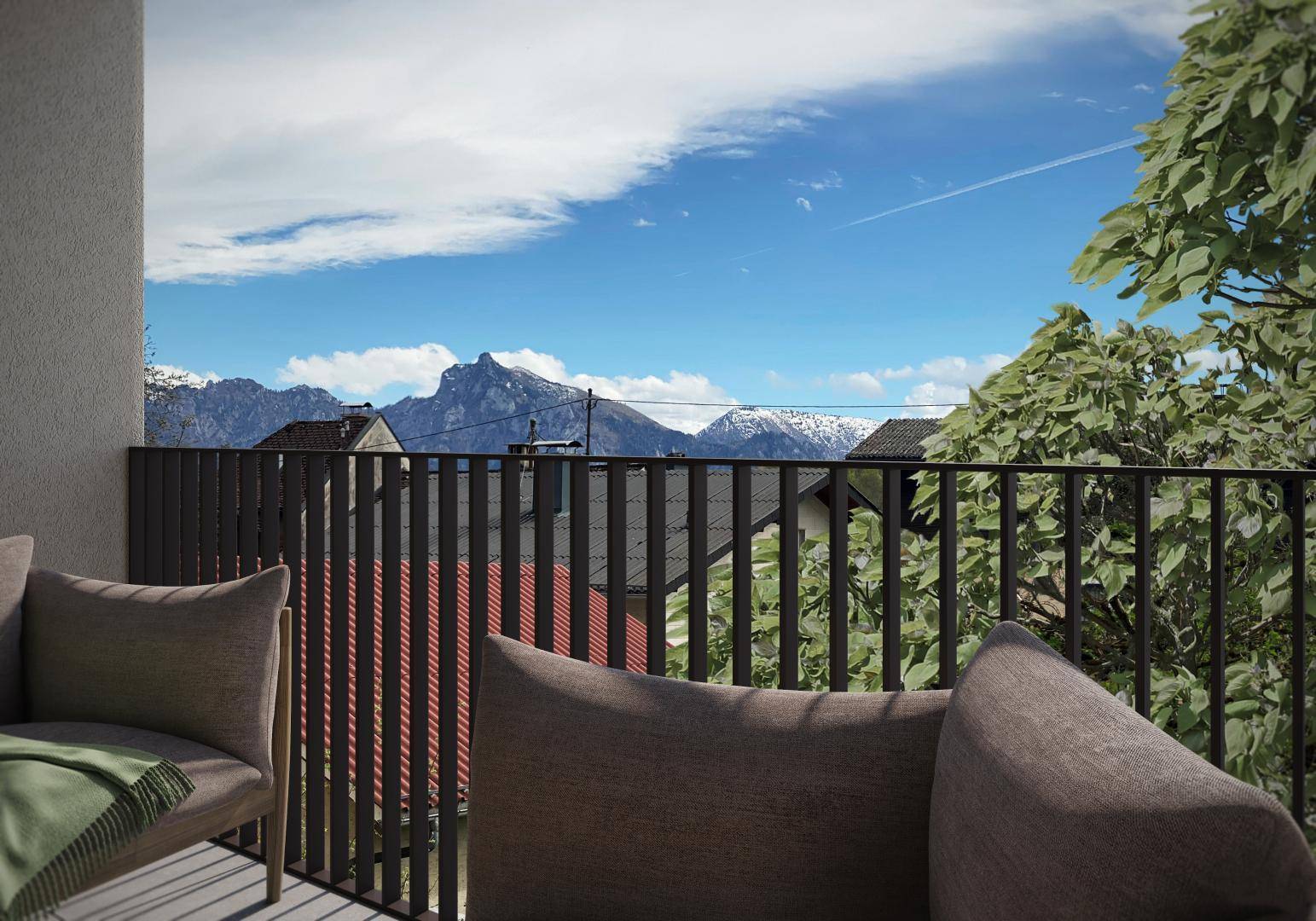 Panoramablick vom Balkon mit bequemen Sitzgelegenheiten auf die schneebedeckten Berge und Dächer.