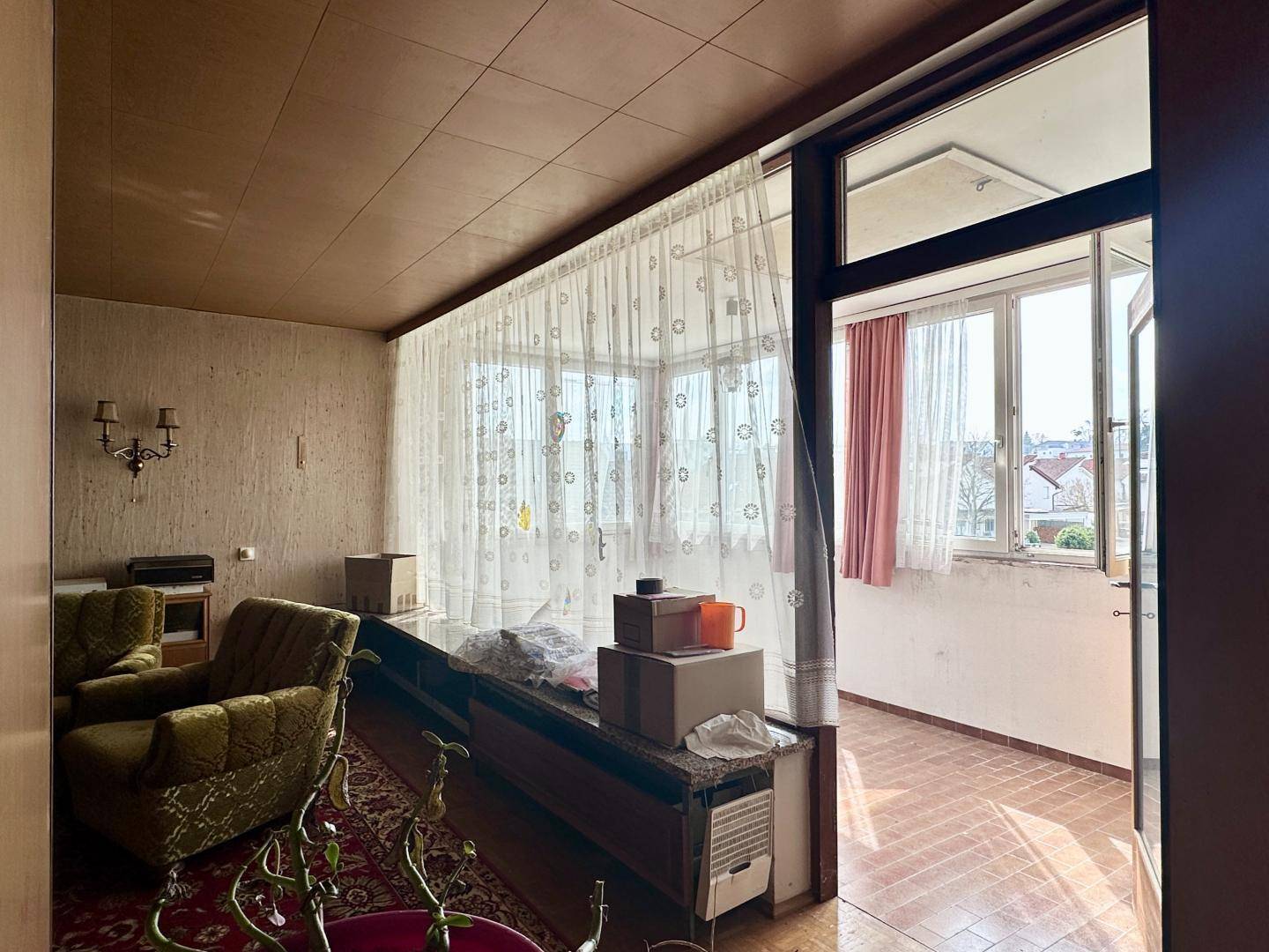 Wohnzimmer mit Zugang zu einem verglasten Balkon, ausgestattet mit Vintage-Möbeln.