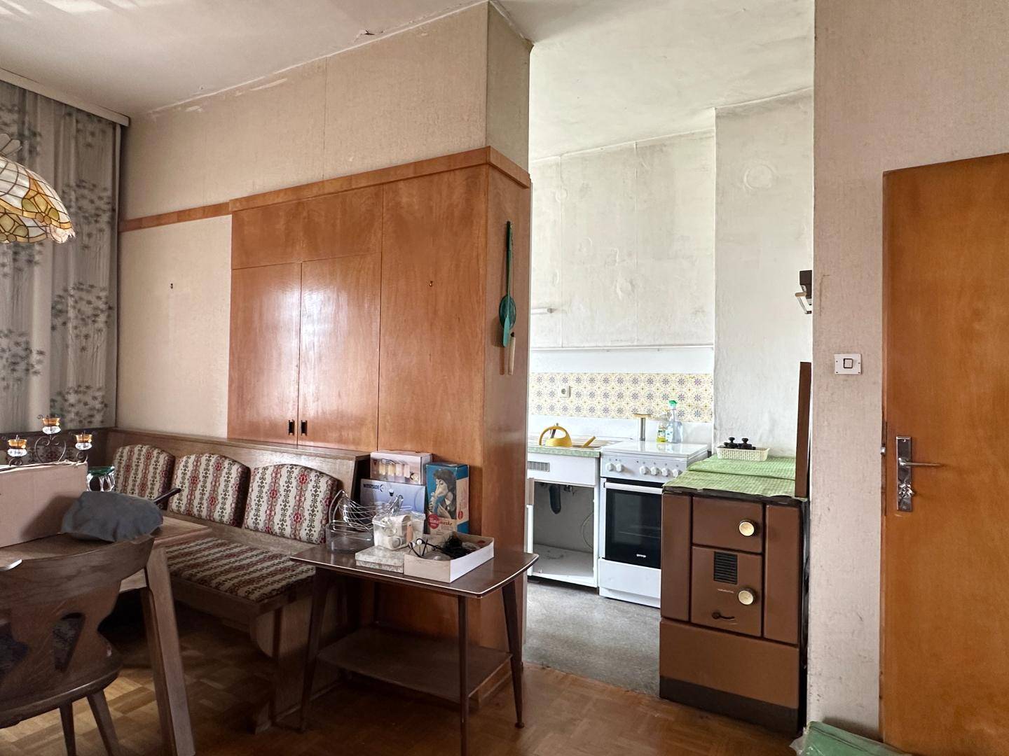 Altes Esszimmer mit Holzmöbeln und Blick in eine einfache, traditionelle Küche.