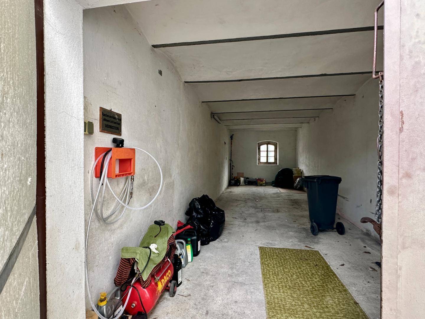 Leere Garage oder Lagerraum mit Betonboden und kleinem Fenster.