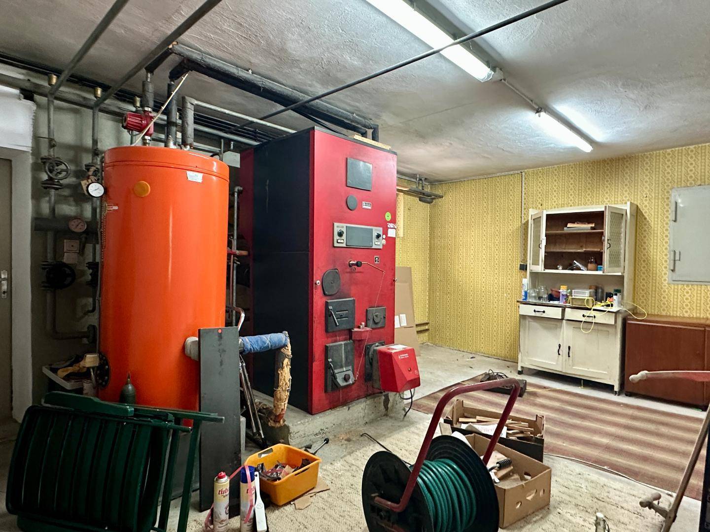 Heizungsraum im Keller mit großem Boiler und Heizkessel, in einem älteren Zustand.