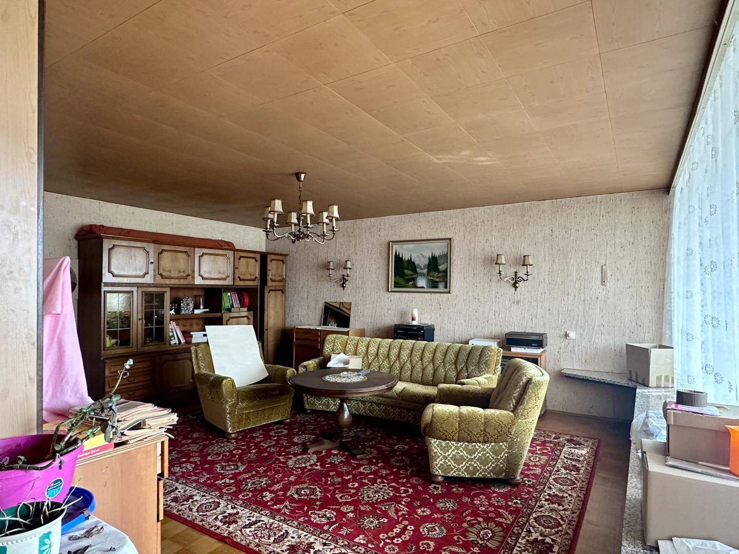 Wohnzimmer im Vintage-Stil mit Teppichboden, Polstermöbeln und Holzschrank.