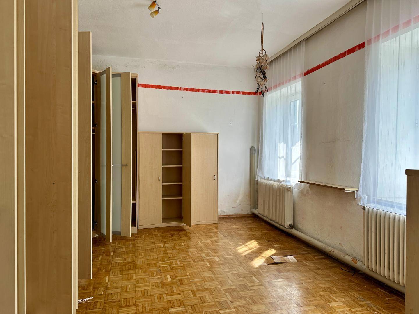 Leeres Zimmer mit Parkettboden, Einbauschränken und natürlichem Lichteinfall.