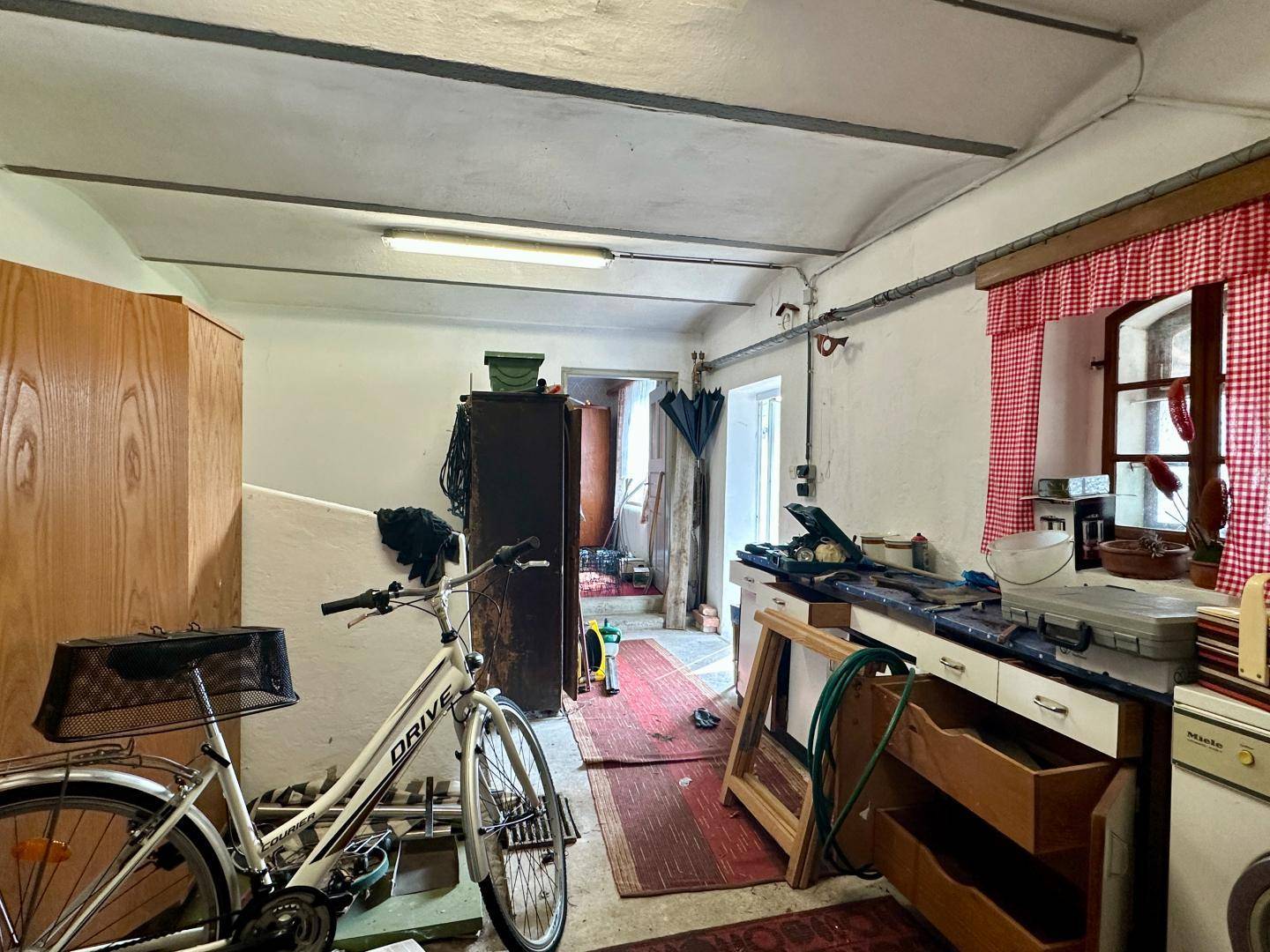 Werkstatt oder Abstellraum im Keller mit Fahrrad und verschiedenen Geräten.