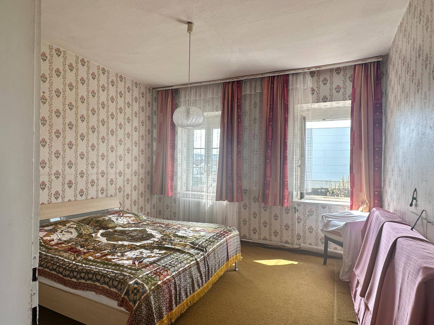 Schlafzimmer im Vintage-Stil mit gemusterter Tapete, Teppichboden und Doppelbett.