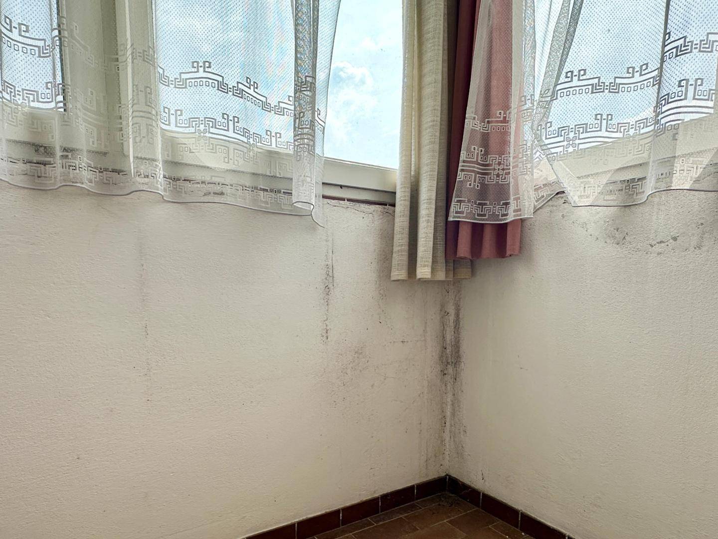 Detailansicht einer Wand im verglasten Balkon mit sichtbaren Verfärbungen.