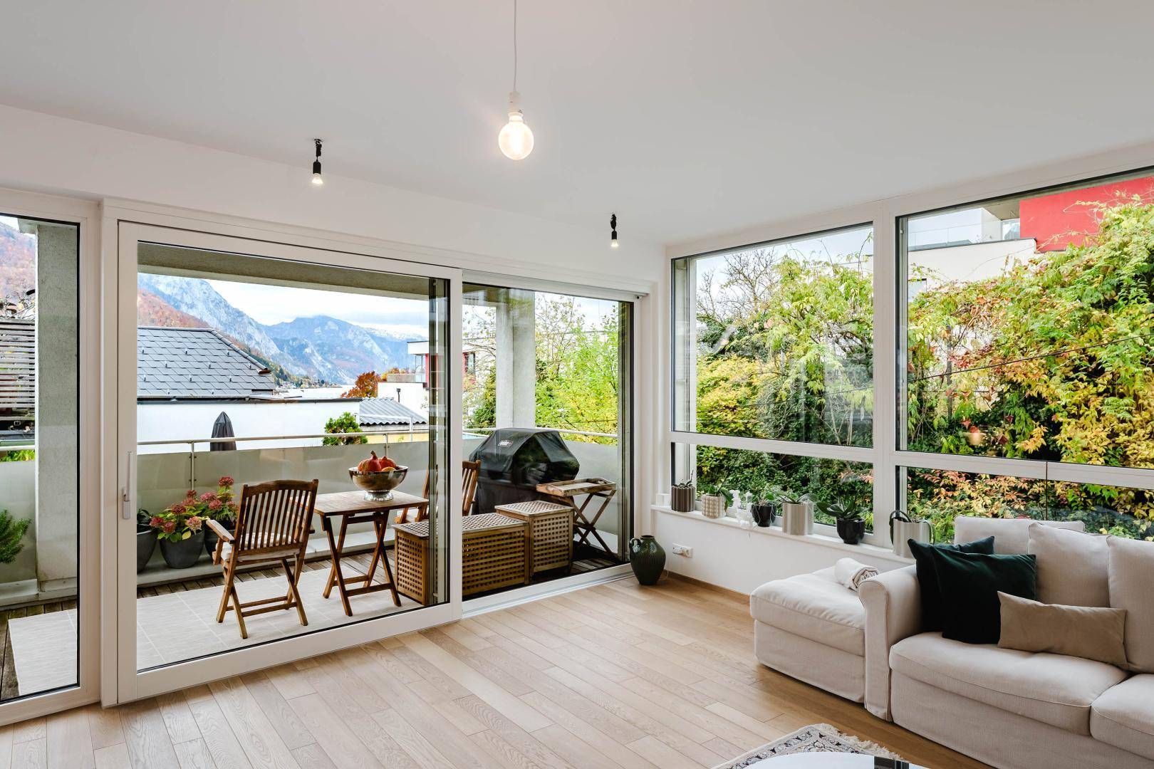 Lichtdurchflutetes Wohnzimmer mit Schiebetüren zum Balkon und Blick ins Grüne.