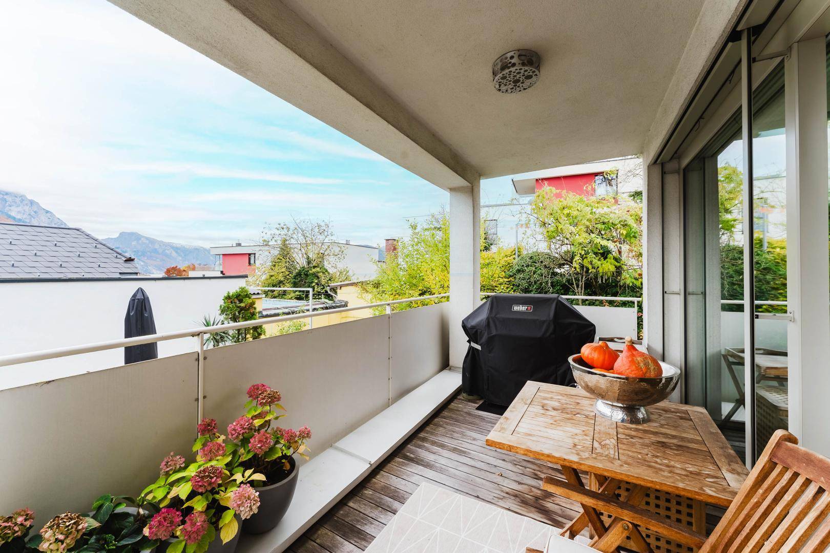 Gemütlicher Balkon mit Holzboden, Sitzgelegenheiten und Bergblick.