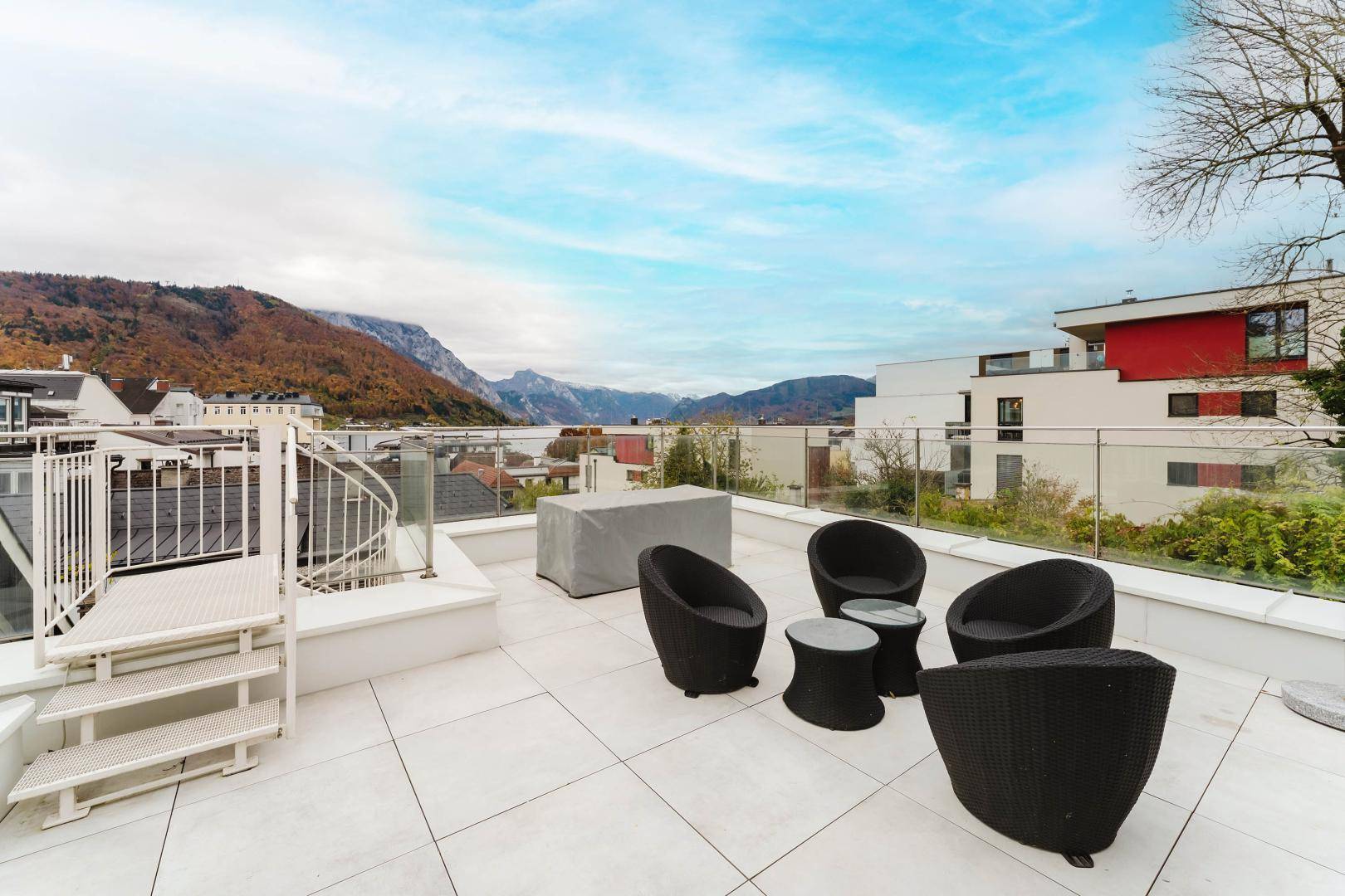 Geräumige Dachterrasse mit modernen Sitzmöbeln und weitem Blick auf den See und die Berge.