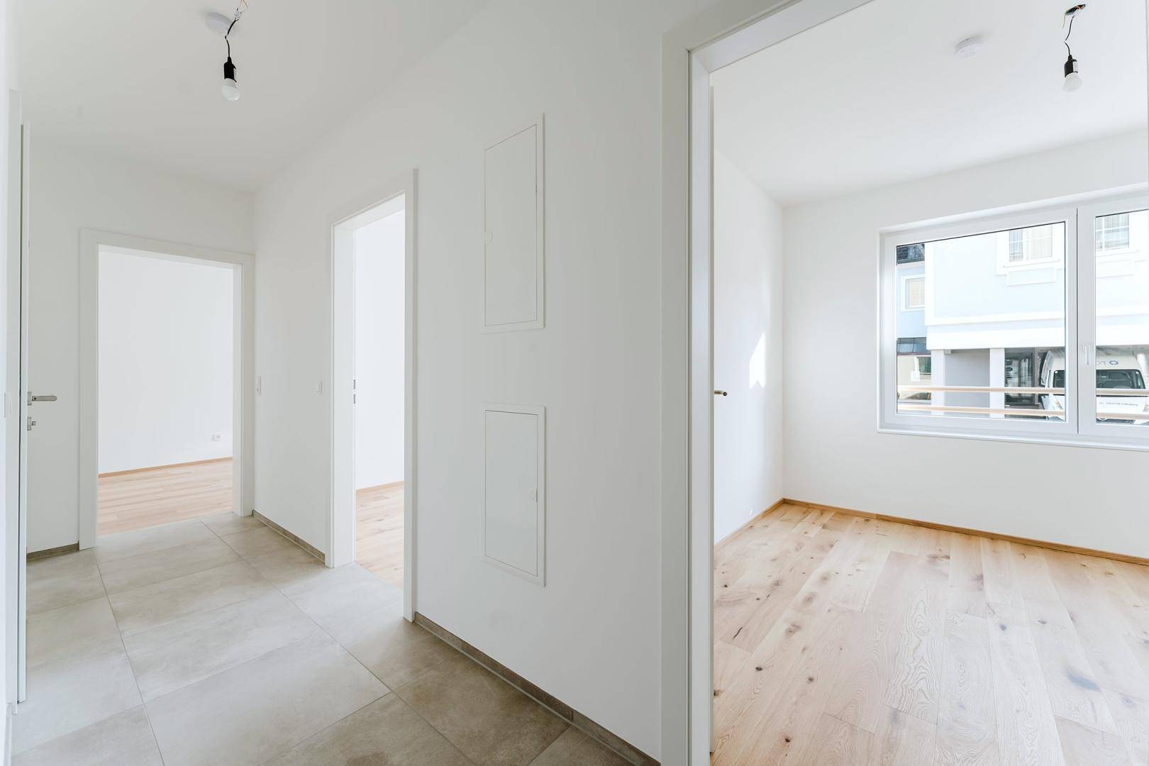 Heller Flur mit Fliesenboden, der zu weiteren Zimmern mit Holzboden führt.