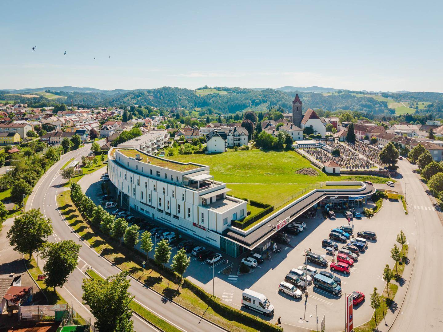 Luftaufnahme des modernen Gebäudes und der umliegenden Stadt mit Kirche und Gräbern.