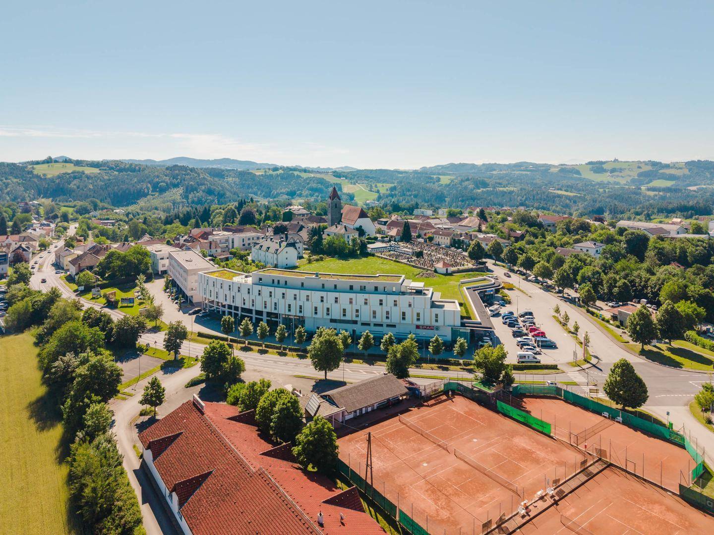 Luftaufnahme des modernen Gebäudes, der Stadt und der nahegelegenen Tennisplätze.
