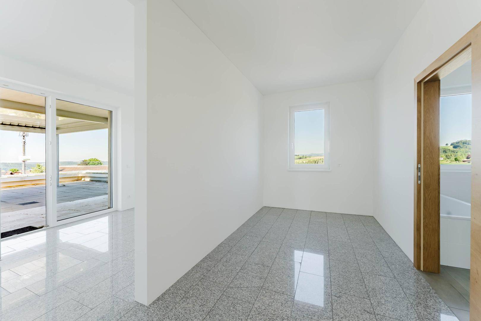 Heller Flur mit glänzendem Fliesenboden und Zugang zur Dachterrasse.
