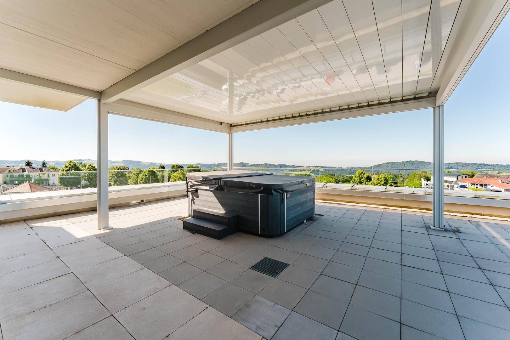 Geräumige Dachterrasse mit überdachtem Whirlpool und Panoramablick auf die Umgebung.