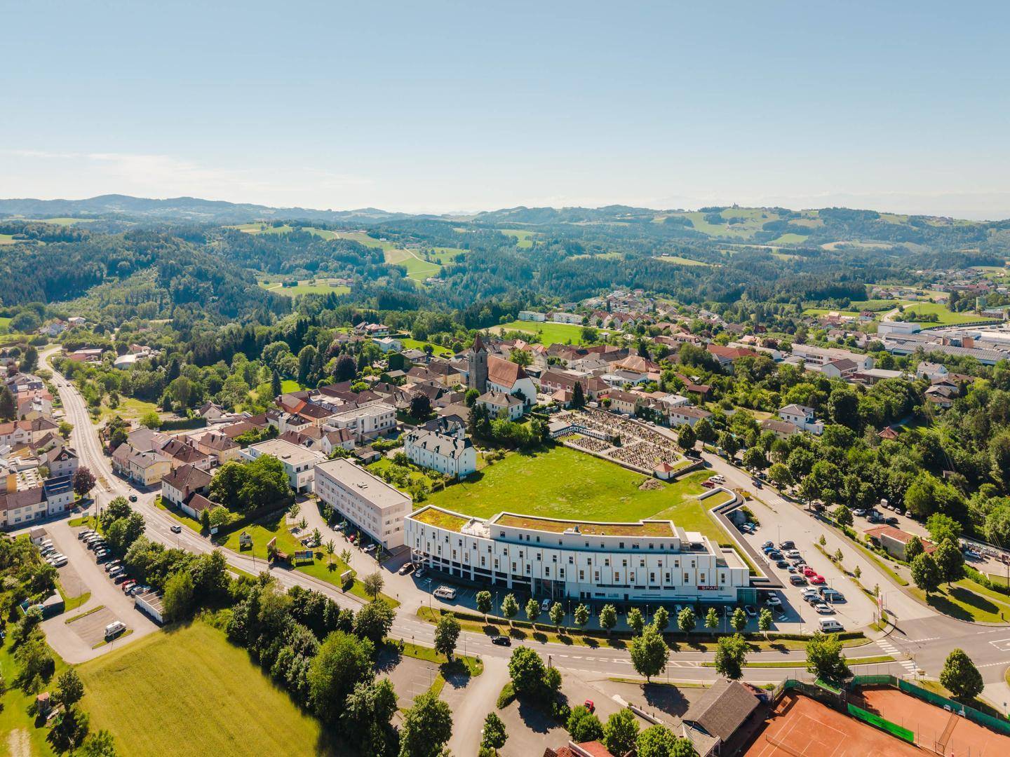 Panoramablick auf die Stadt, das moderne Gebäude und die umliegende grüne Landschaft.