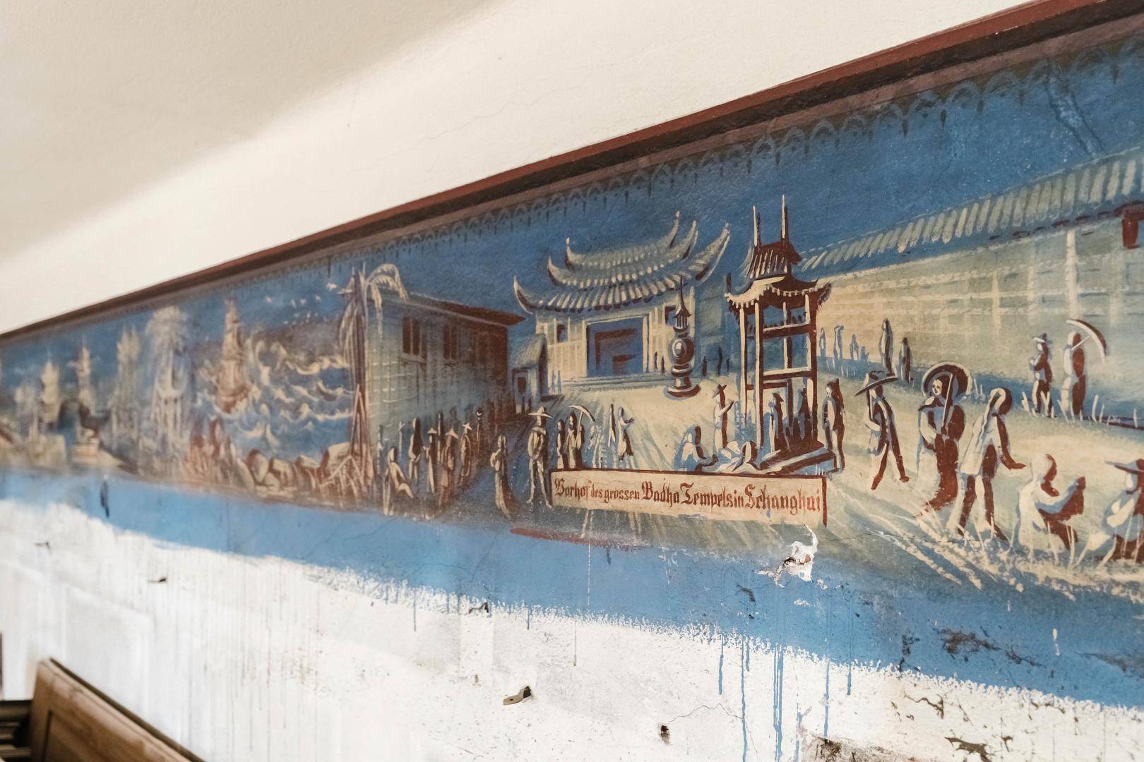 Nahaufnahme eines historischen Wandgemäldes mit asiatischen Motiven und Schriftzeichen.