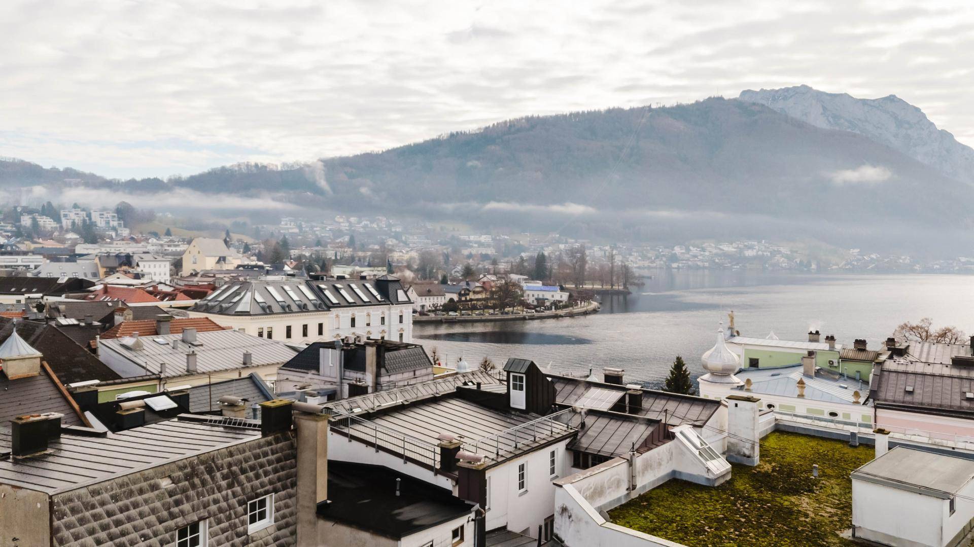 Panoramablick von den Dächern der Stadt auf den See und die nebelverhangenen Berge.