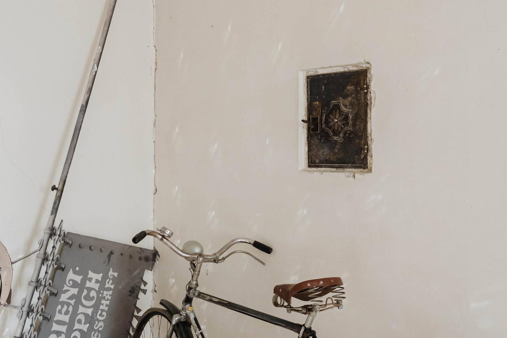 Detailansicht einer Wand mit einem historischen Safe und einem Fahrrad im Vordergrund.