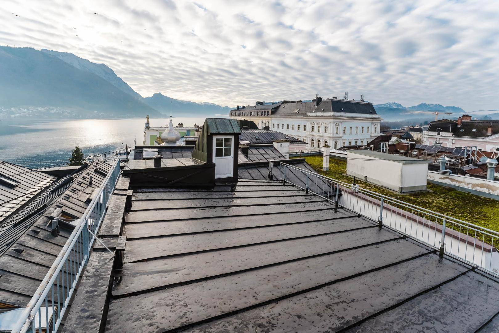 Dachterrasse mit weitem Blick über die Stadt, den See und die umliegenden Berge.