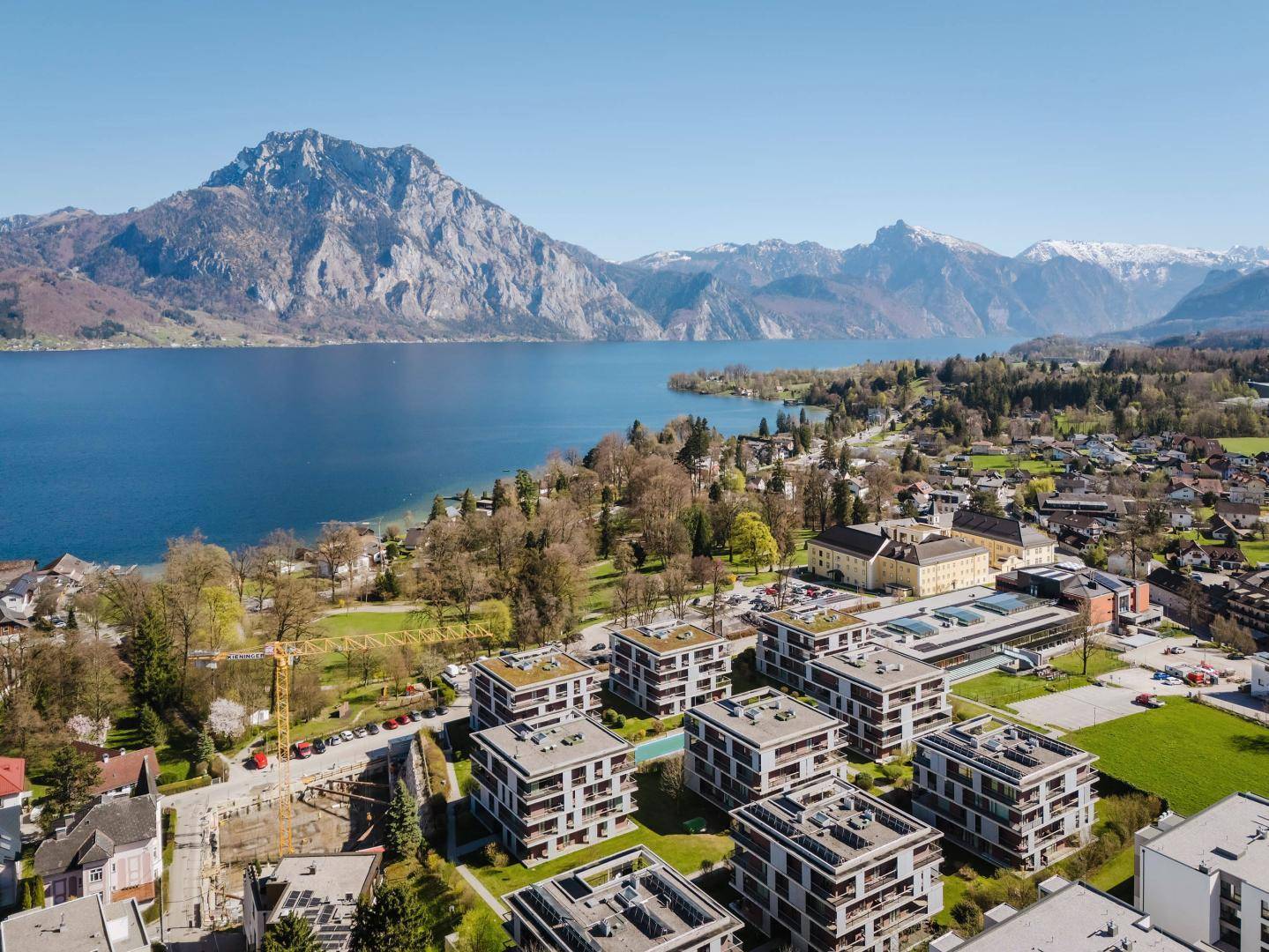 Weitläufige Wohnanlage mit mehreren modernen Gebäuden, See- und Bergblick in sonniger Umgebung.