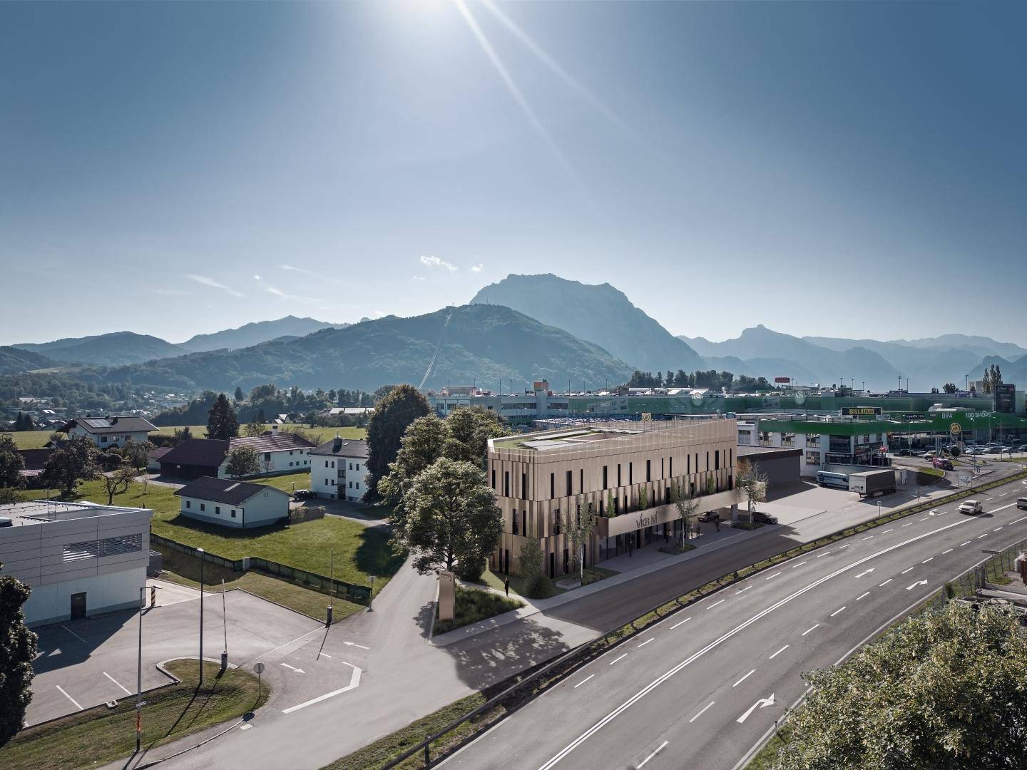 Luftaufnahme-Visualisierung des Bürogebäudes mit umliegender Landschaft, Bergen im Hintergrund und Sonnenschein.