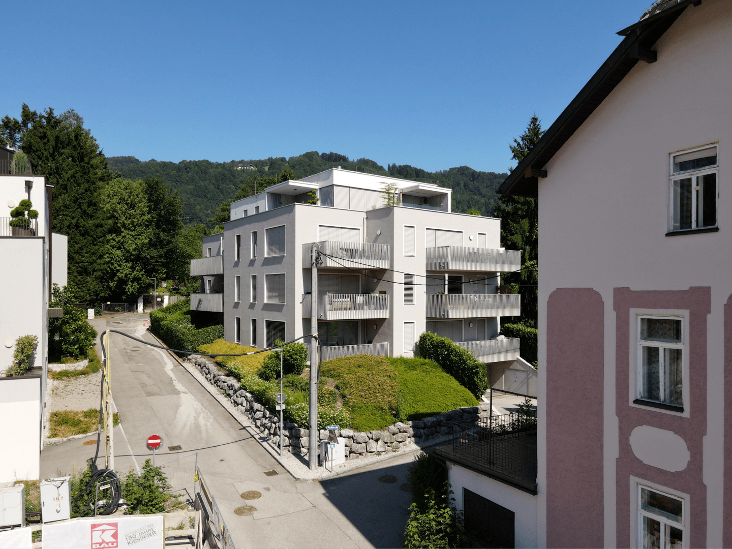Moderne Wohnanlage mit Balkonen und Blick auf die umliegende grüne Hügellandschaft.