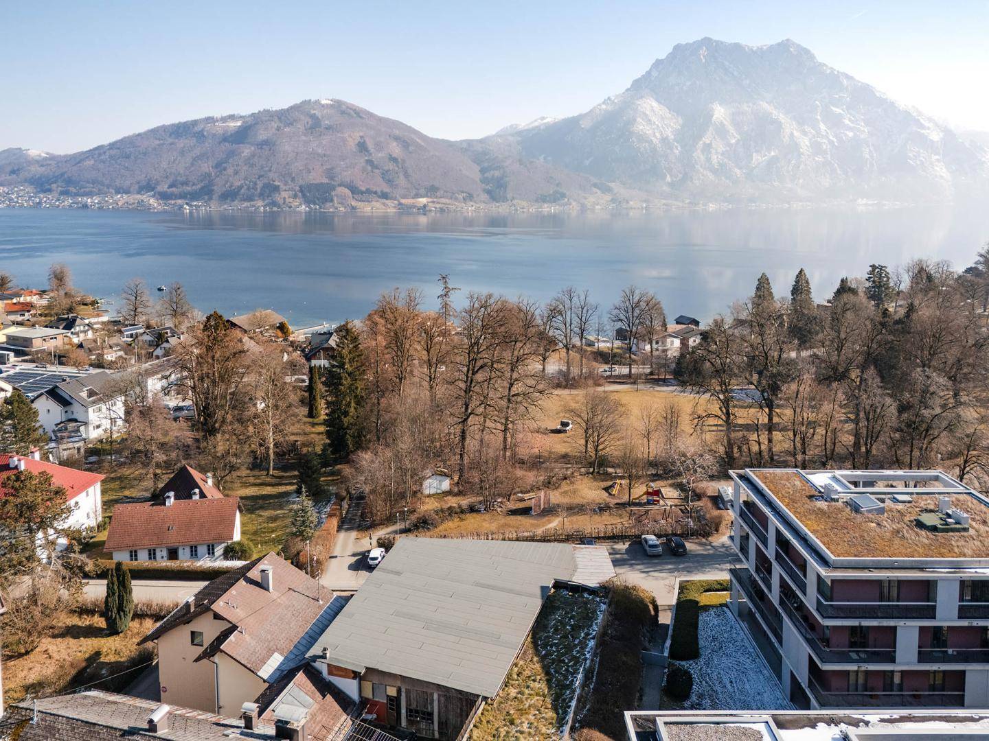 Winterliche Stadtansicht mit See, Bergen und umliegenden Gebäuden.