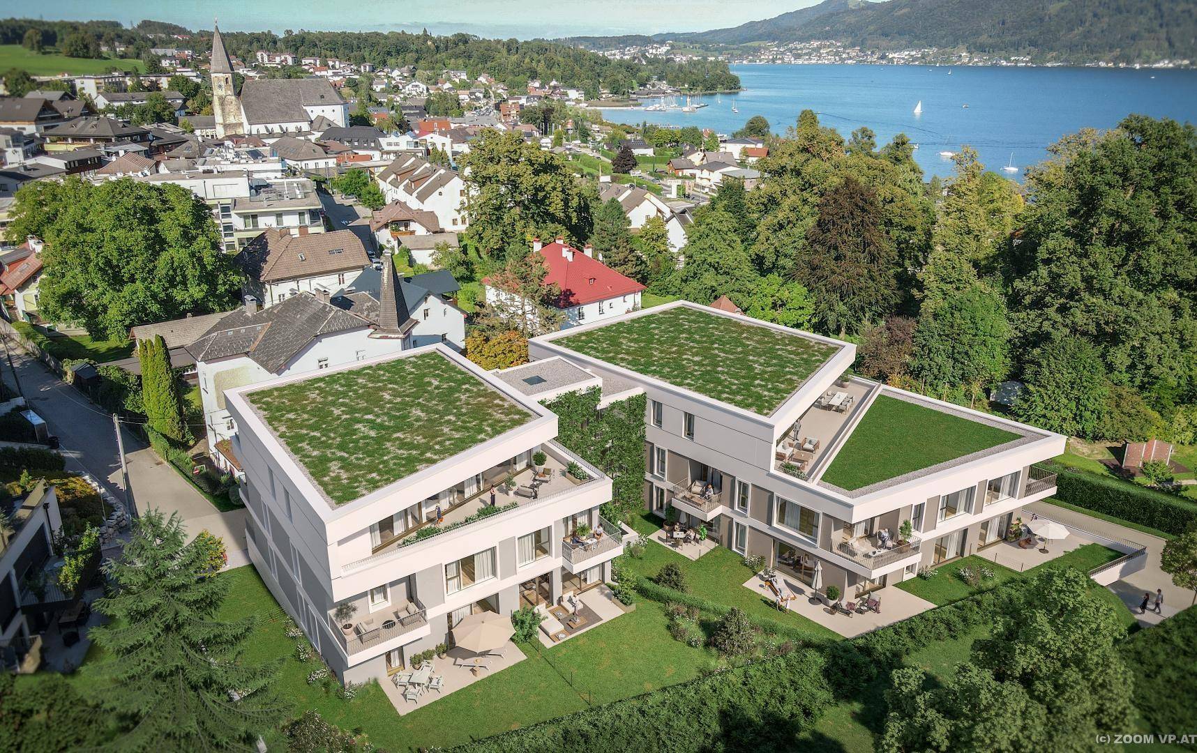 Neubauwohnungen mit begrünten Dächern in einer malerischen Stadtlage mit Blick auf den See.