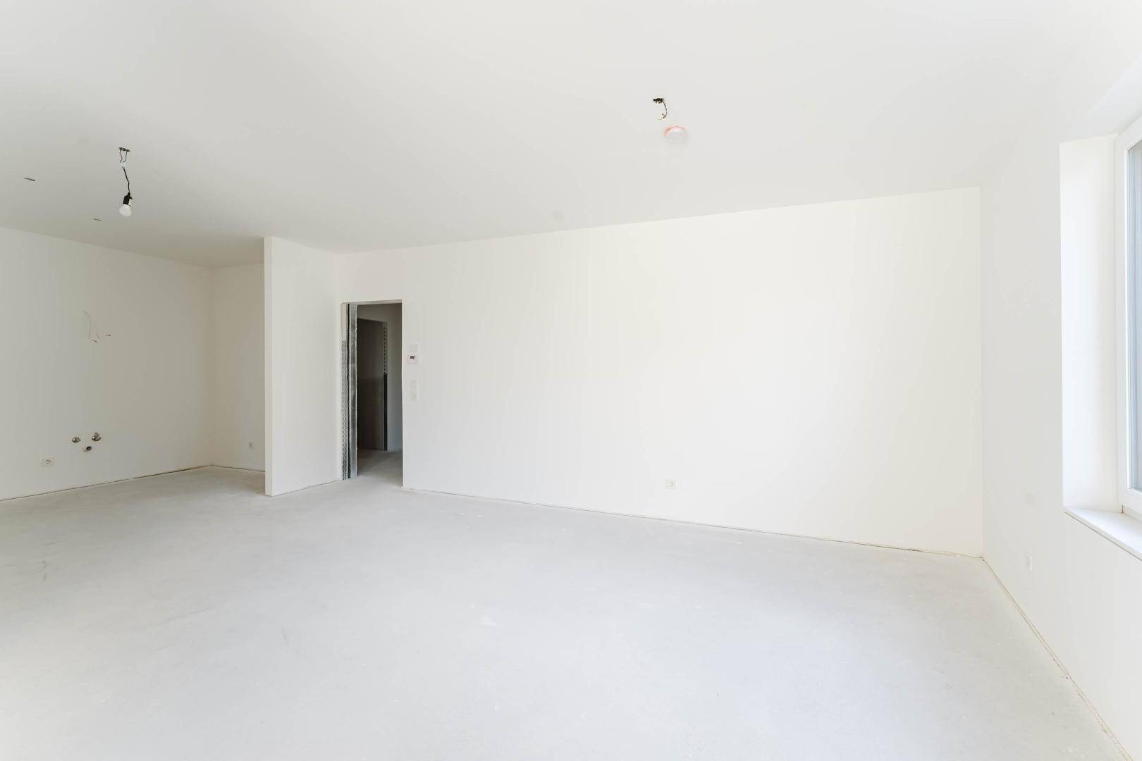 Unmöblierter Raum mit weißen Wänden und einem Türrahmen zu einem weiteren Zimmer.