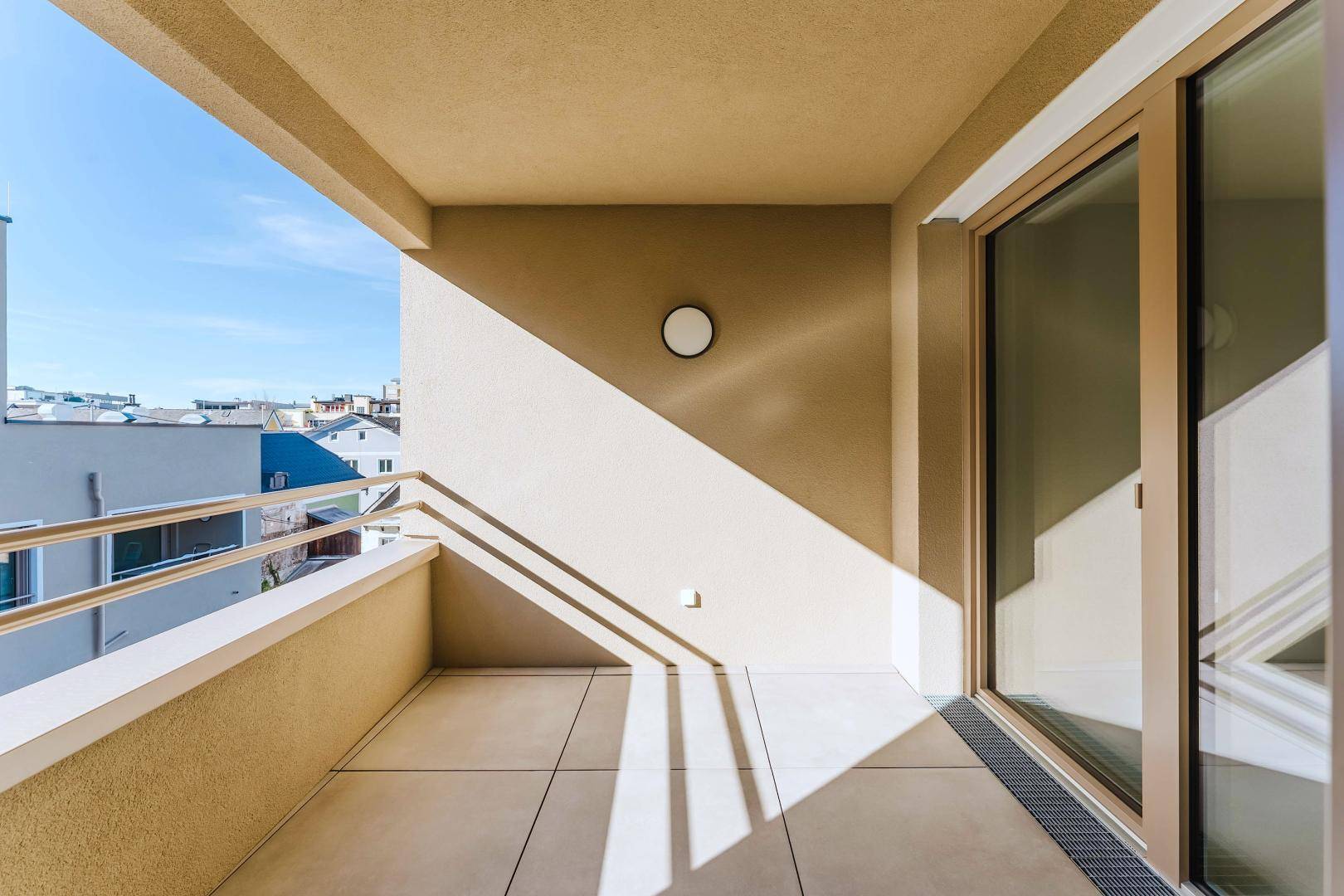Heller Balkon mit Fliesenboden und Blick auf die umliegenden Gebäude.