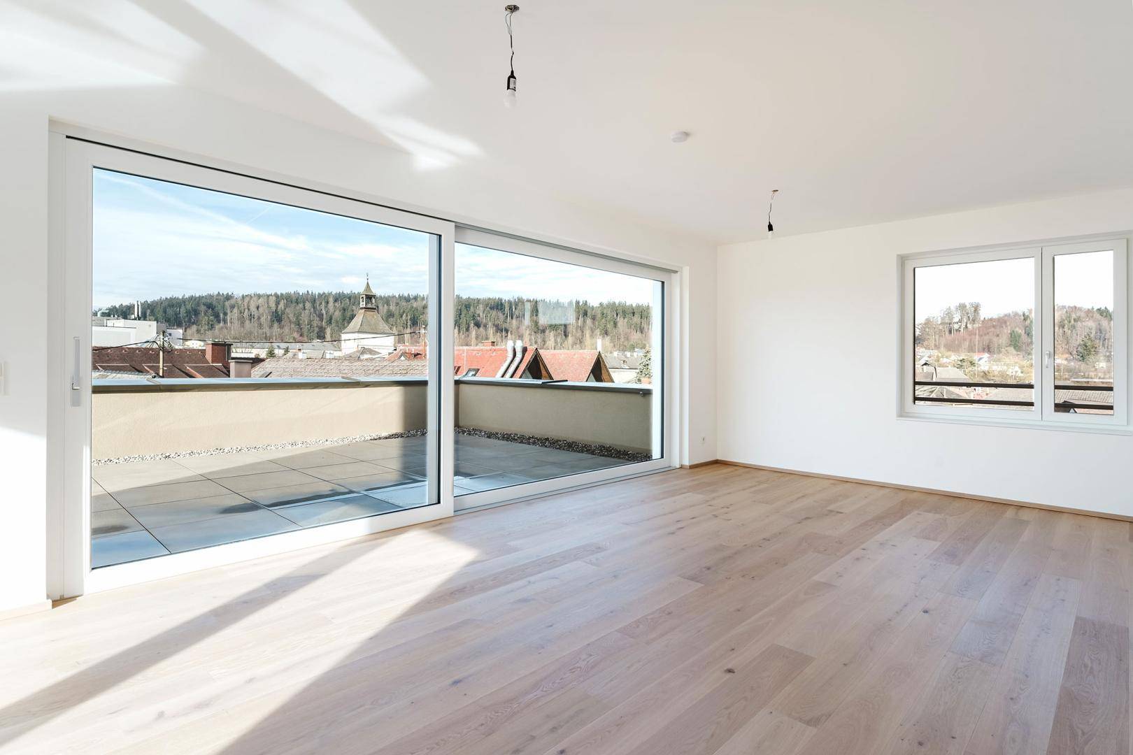 Heller, leerer Raum mit großen Schiebetüren zum Außenbereich und weitem Blick.
