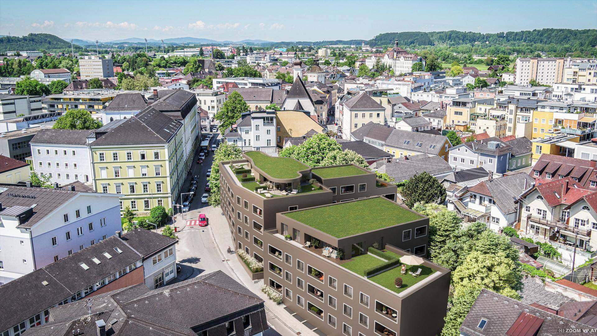 Luftaufnahme eines modernen Gebäudekomplexes mit begrünten Dächern in städtischer Umgebung.