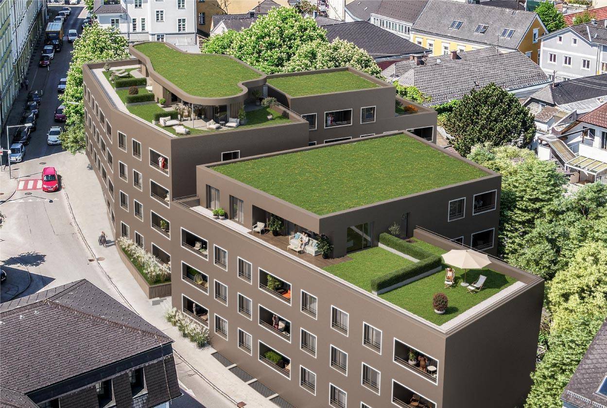 Moderne Wohnanlage mit begrünten Dächern und Balkonen in städtischer Umgebung.