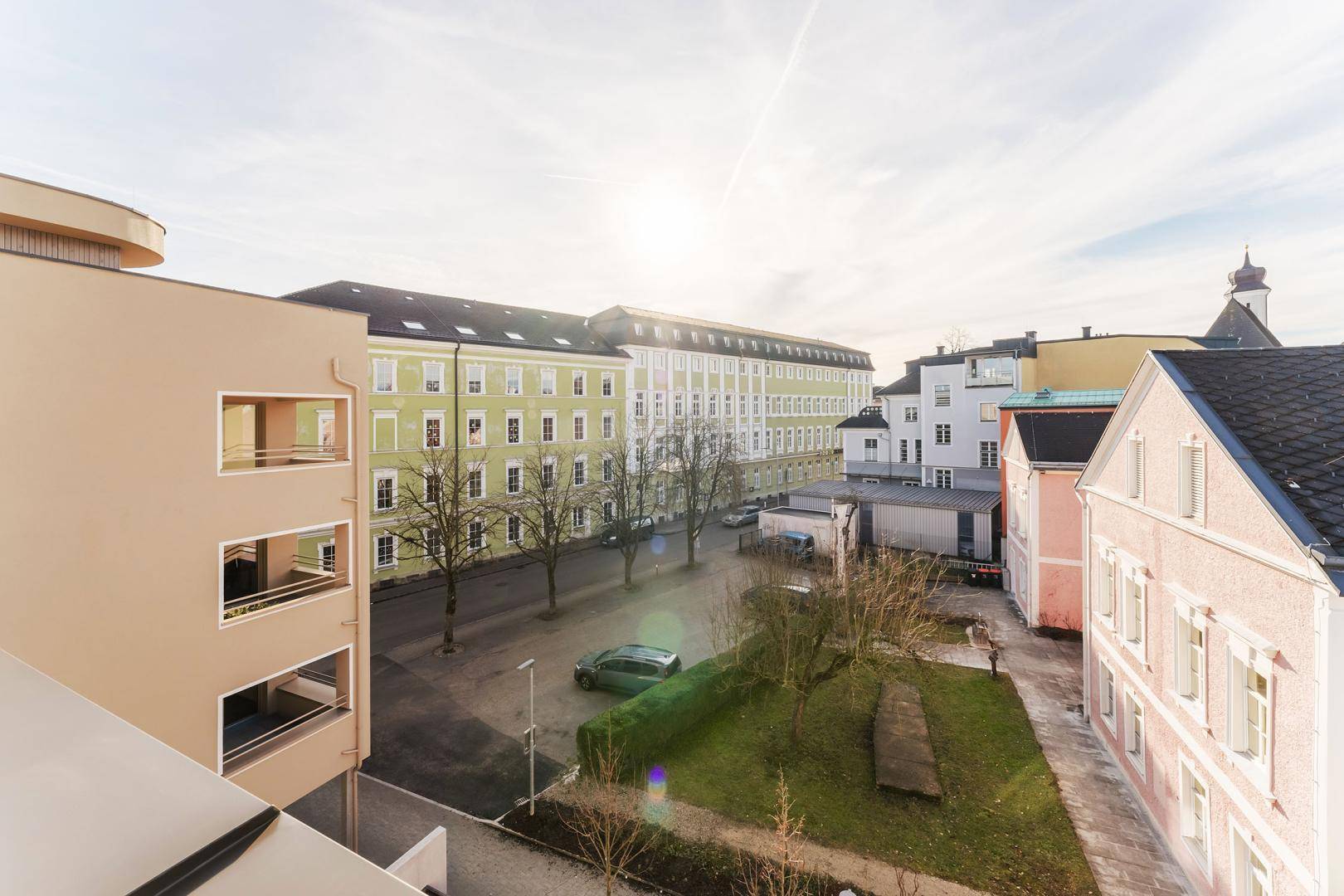 Panoramablick auf eine ruhige Straße mit historischen Gebäuden und Bäumen an einem sonnigen Tag.