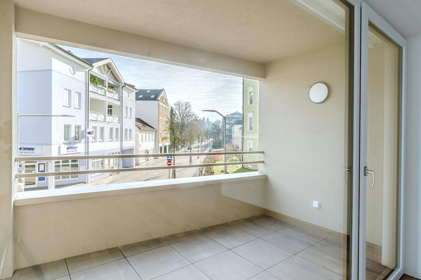 Balkon mit Fliesenboden und Blick auf die umliegende Stadtstraße und Gebäude.