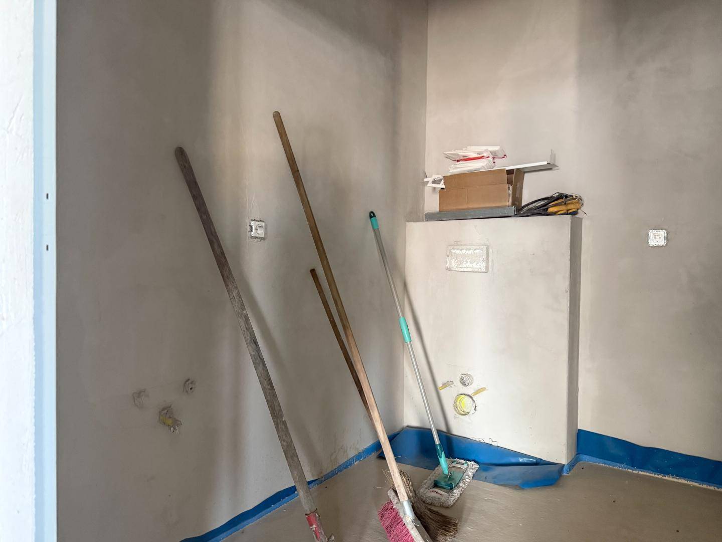 Unfertiger Raum mit Rohbauwänden und Anschlüssen, möglicherweise für ein Badezimmer oder einen Abstellraum.